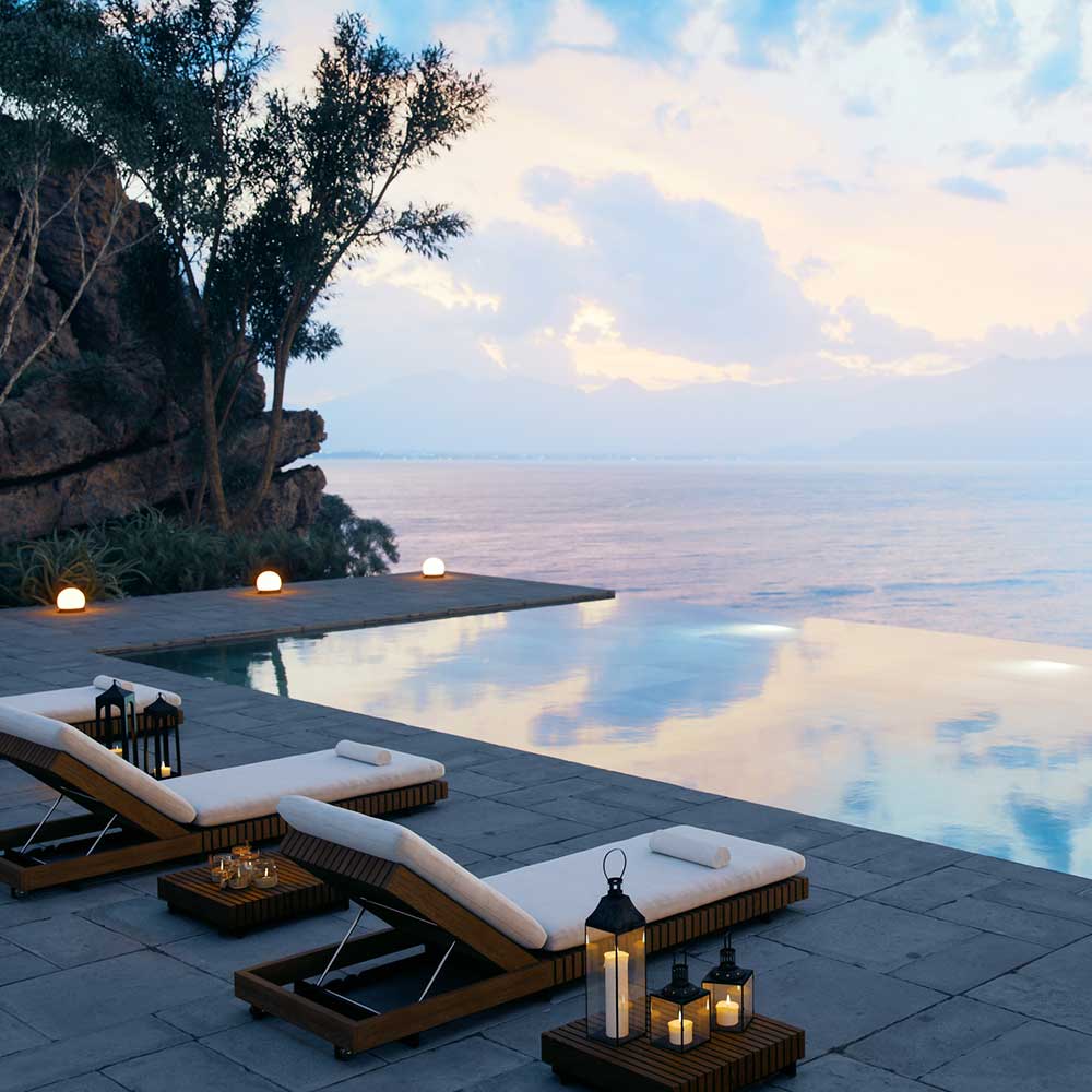 Lounge chairs by still water at sunset